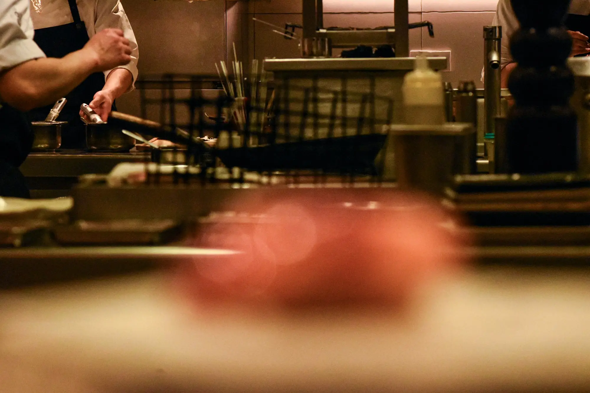 Chefs working in a busy commercial kitchen full of cooking equipment